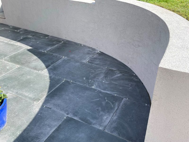 Curved rendered wall with charcoal porcelain paving
