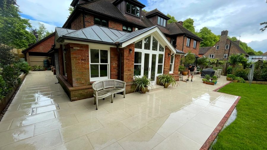Sandstone patio and lawn behind a detached house